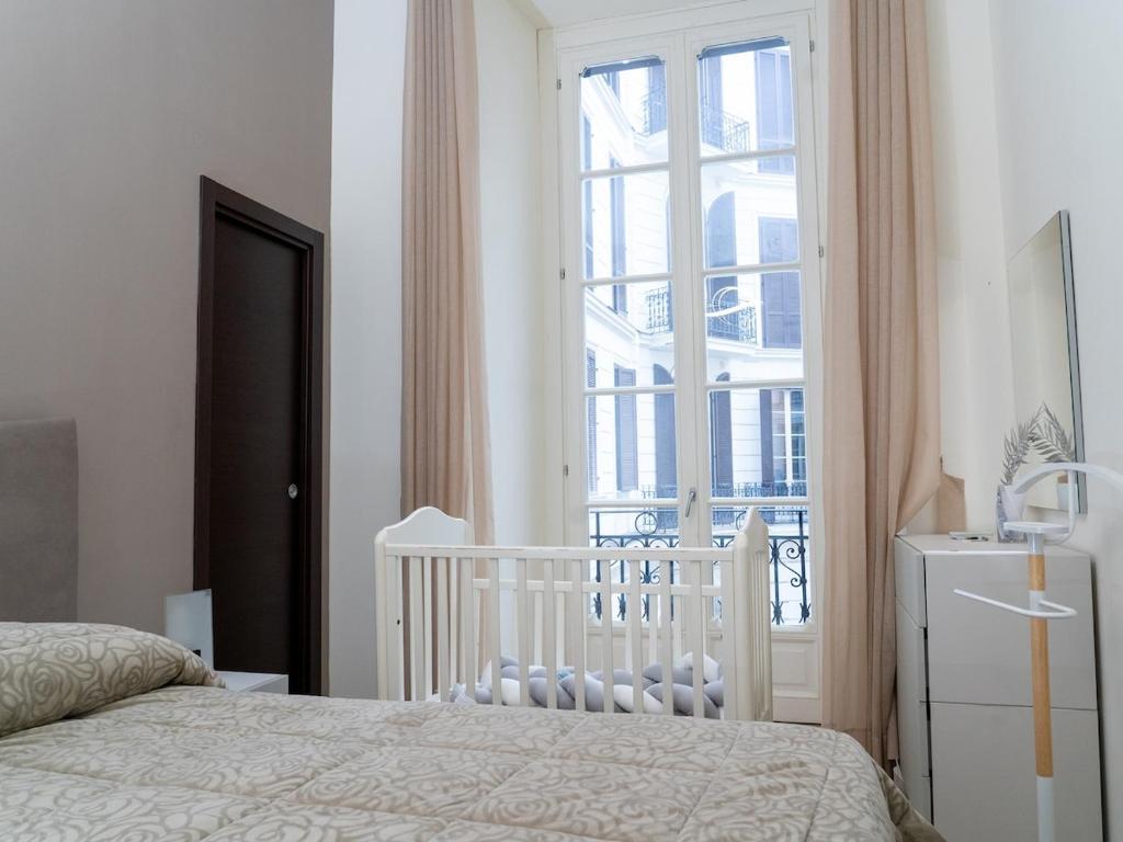 Calm bedroom with tall French windows and a cot